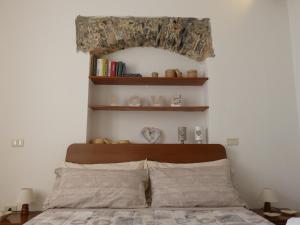 a bedroom with a bed with a wooden headboard and shelves at LA VALLETTA SUL MARE in La Spezia