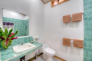 ein Badezimmer mit einem Waschbecken, einem WC und einem Spiegel in der Unterkunft Yucca Beachfront Hotel in Puerto Viejo