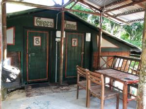 a green building with a wooden bench and a table at Dragon Pearl Beach Resort in Kota Belud