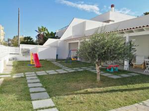 um quintal com uma árvore e um parque infantil em Little house em Mazara del Vallo