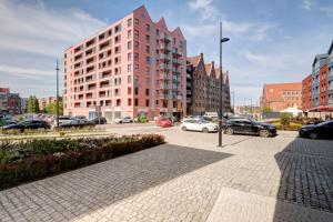 een parkeerplaats met auto's geparkeerd voor een hoog gebouw bij Live & Travel Apartments - Waterlane Island in Gdańsk