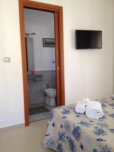 a bedroom with a bed and a bathroom with a toilet at La Castellese in Aci Castello