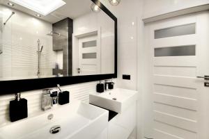 a white bathroom with a sink and a mirror at Bulwary Wislane P&O Serviced Apartments with AC in Warsaw +23 photos