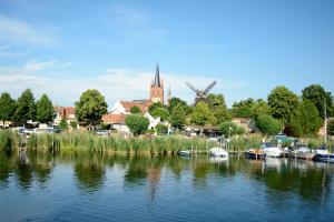 eine Gruppe von Booten in einem Fluss mit einer Kirche in der Unterkunft Lendelhaus & Historische Saftfabrik Werder in Werder