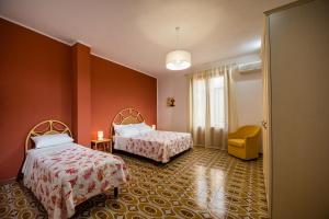ein Hotelzimmer mit 2 Betten und einem gelben Stuhl in der Unterkunft Casa dei Coralli in Castellammare del Golfo
