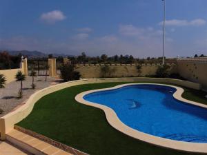 a swimming pool in a yard with a green lawn at Casa Nikki in Mazarrón