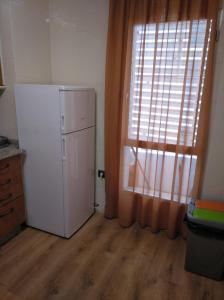 uma cozinha com um frigorífico branco e uma janela em Manolo piso em Portomarin