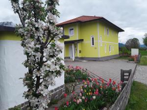żółty dom z kwiatami przed nim w obiekcie Apartments Steger w mieście Faak am See