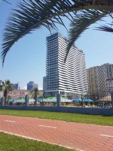 a tall building with a palm tree in front of it at Orbi Residence Apartments in Batumi