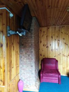 Hostel Hola في تشيرنيهيفسكا: كرسي احمر جالس في غرفة فيها تلفزيون