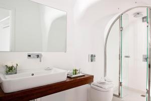 a bathroom with a shower, sink, and toilet at Canaves Oia Boutique Hotel in Oia
