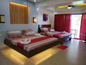 two beds in a bedroom with red curtains at Bellevue Resort in Puerto Galera