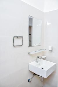 Baño blanco con lavabo y espejo en Saman Beach Guest House en Galle