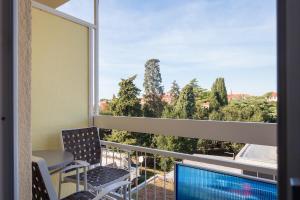einen Balkon mit Blick auf den Pool und die Bäume in der Unterkunft Hotel Porec in Poreč