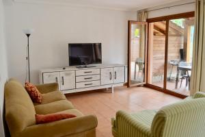 ein Wohnzimmer mit einem TV und einem Sofa in der Unterkunft Chalet adosado en Costa Miño a un paso de la playa in Miño