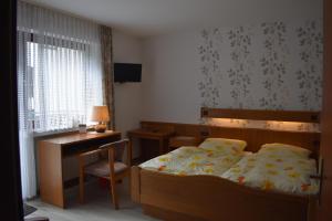 um quarto com uma cama e uma secretária. em Pension Haus am Waldesrand em Schieder-Schwalenberg
