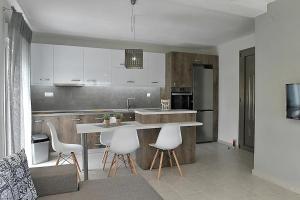 a kitchen with a table and some white chairs at Crystallia SeaSide Maisonette by RentalsPro- Nea Moudania in Nea Moudania