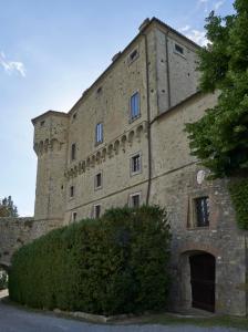 ein großes Backsteingebäude mit einem Baum davor in der Unterkunft Castello di Fighine in San Casciano dei Bagni