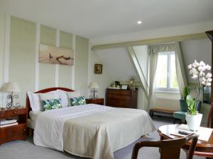 a bedroom with a large white bed and a table at Chambres d'Hôtes Les Vieilles Digues in Beauvoir