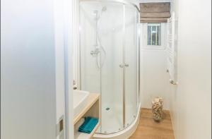 a white bathroom with a shower and a sink at Mobilheim Murnersee Haus 5 in Wackersdorf