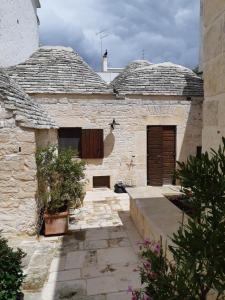 an old stone building with a door and some plants at Alberobello Casa Vacanze - Pathos tra i Trulli in Alberobello