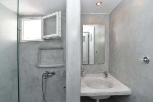een badkamer met een wastafel, een douche en een spiegel bij Eleftheria Veloudiou in Tinos Town