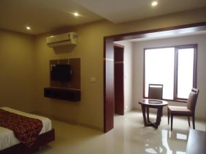 a bedroom with a bed and a table and a tv at Pleasant Inn in Pondicherry
