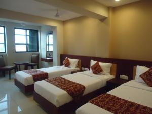 a hotel room with three beds and a table at Pleasant Inn in Puducherry