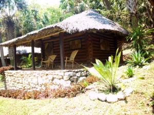 Cabaña de madera con sillas y techo de paja en Cabañas Sierraverde Huasteca Potosina, en Tamasopo