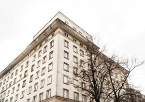 wysoki biały budynek z drzewem przed nim w obiekcie Dworzec Centralny P&O Serviced Apartments w Warszawie