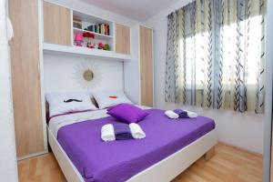 a bedroom with a purple bed with towels on it at Apartment Tropic Stobrec in Split