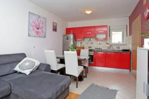 uma sala de estar com um sofá e uma cozinha com armários vermelhos em Apartment Tropic Stobrec em Split