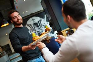 a man handing a tray of food to another man at St Christopher's Inn Paris - Canal in Paris