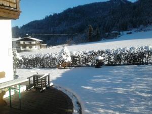 einen schneebedeckten Hof mit einer Bank und einen schneebedeckten Zaun in der Unterkunft Lärcheck in Ramsau bei Berchtesgaden