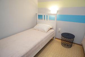 a small bedroom with a white bed and a stool at Apartment Marko in Crveni Vrh