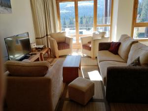 a living room with couches and a tv at Flaine prime ski in, ski out Apartment in Flaine