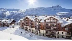 um grupo de edifícios na neve com montanhas em Flaine prime ski in, ski out Apartment em Flaine