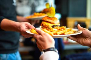 a person holding a plate with a sandwich and french fries at St Christopher's Inn Paris - Canal in Paris