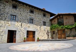 duży kamienny budynek z drewnianymi drzwiami i oknami w obiekcie Casa Rural Garabilla w mieście Santa Coloma