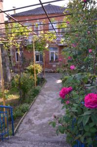 a garden with pink roses and a brick house at Friends House in Kutaisi