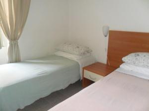 Cette petite chambre comprend deux lits. une table de nuit dans l'établissement Albergo Romeo, à Noli