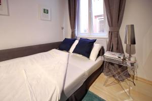 a bed with blue pillows and a window in a room at Globe Apartament 2 in Zadar