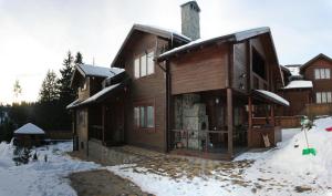 a large wooden house with snow on the ground at Villa Monte in Slavske