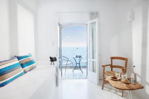 Sala de estar blanca con mesa y vistas al océano en Karma Minoan, en Agios Nikolaos