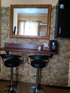 a bar with two stools and a mirror on a stone wall at Gina B&B in Rome