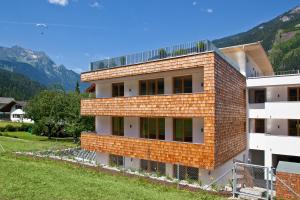 a red brick building with a mountain in the background at Apart Mountain Lodge Mayrhofen in Mayrhofen