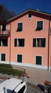 pomarańczowy budynek z samochodem zaparkowanym przed nim w obiekcie Affittacamere B&B Trattoria della Posta w mieście Maissana