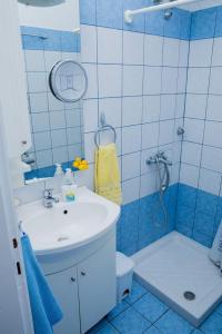 y baño azul y blanco con lavabo y ducha. en Villa Pleiades #1, en Vrasná