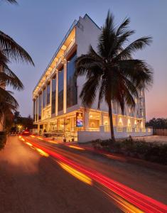 Devanhalli的住宿－Shivas Galaxy Hotel，街道前有棕榈树的建筑
