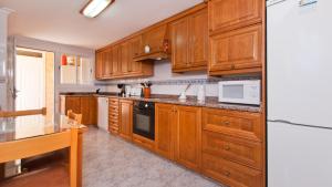 a kitchen with wooden cabinets and a refrigerator at C237 Estrella Azul by Mallorca Villa Selection in Alcudia